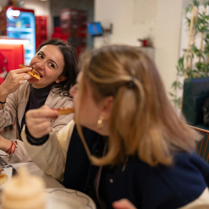 Testaccio-food-tour Two young women eating traditional Roman pizza al taglio in Testaccio, Rome