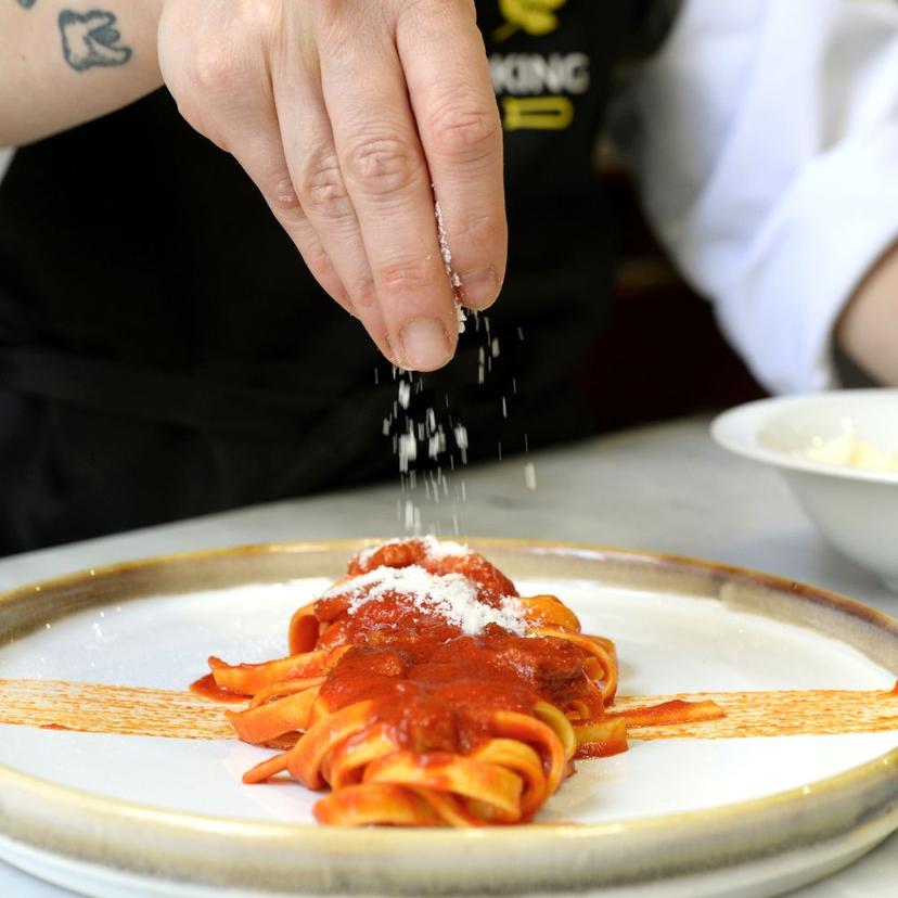fettuccine-amatriciana Hand sprinkling cheese over fettuccine all'Amatriciana