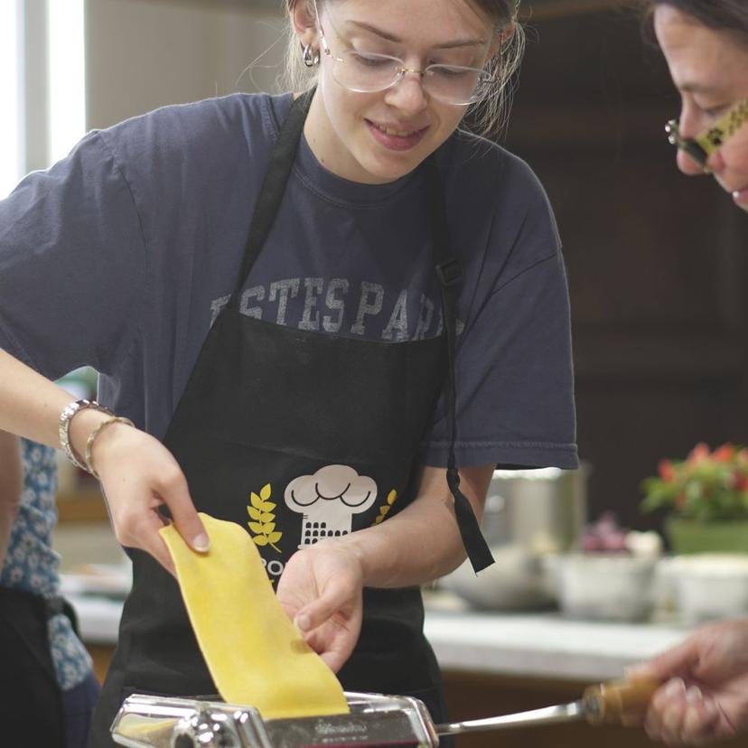 Girls using pasta maker girls placing raw pasta dough into pasta maker
